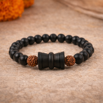 A spiritual healing bracelet featuring alternating 8mm natural brown Rudraksha beads and polished black Karungali (Ebony wood) beads. The center features a detailed silver-toned Damru charm, symbolizing Lord Shiva's energy, all strung on a durable elastic cord.