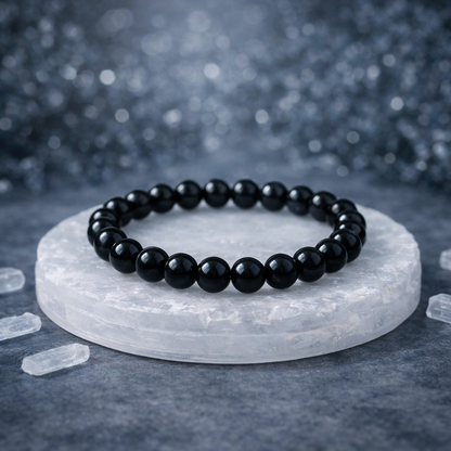 A protective spiritual set featuring a Black Obsidian bead bracelet resting on a rectangular raw Selenite charging plate. The deep, jet-black glossy obsidian beads contrast sharply with the white, satiny, and fibrous texture of the natural Selenite slab.
