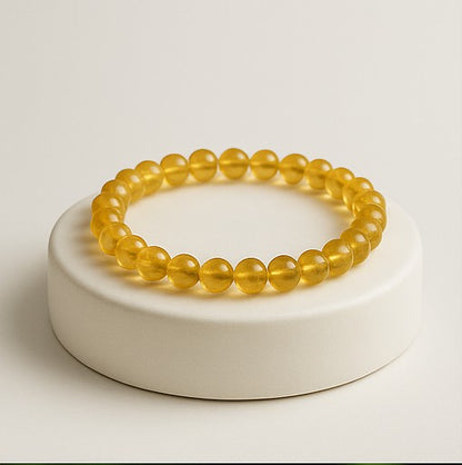 Natural yellow Citrine beaded bracelet resting on a raw white Selenite charging plate for wealth and energy cleansing.