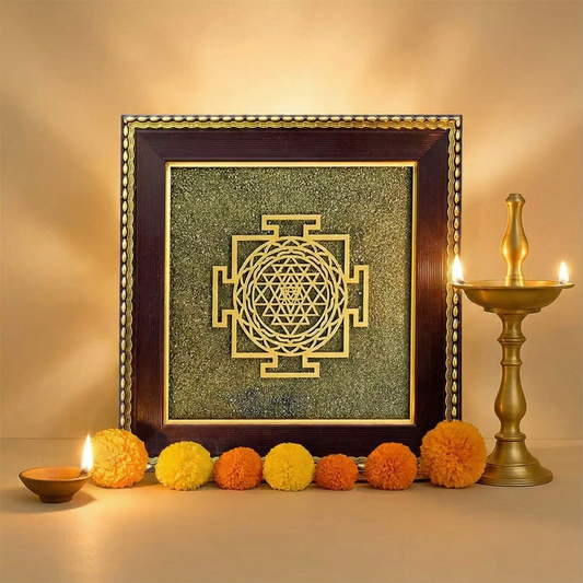 Decorative wall art with a Sri Yantra design in a wooden frame, surrounded by colorful pom-poms and candles.